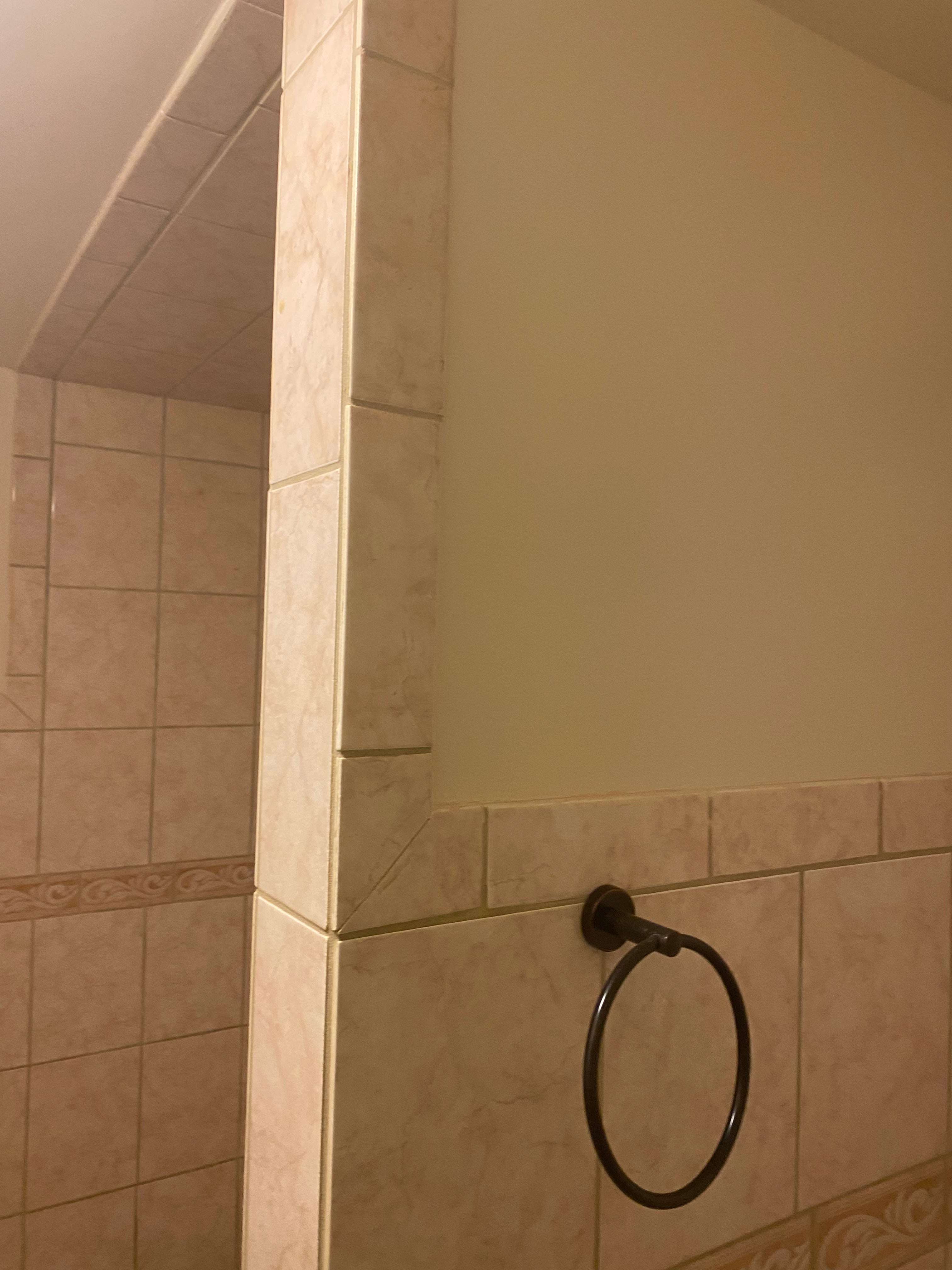 Towel rack on a tiled bathroom wall with a mirror above