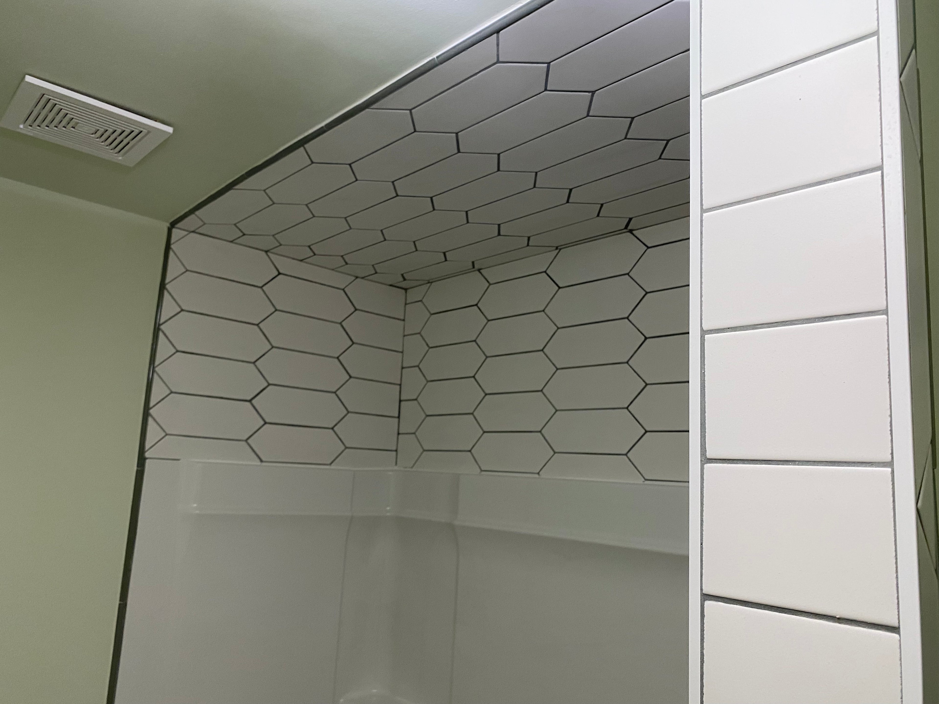 Bathroom corner with hexagonal white tiles and a shower area.