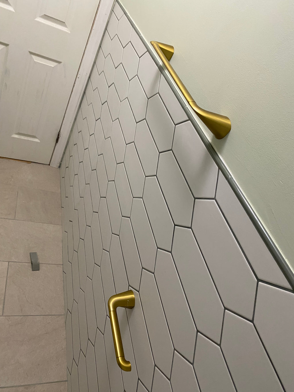 Gold towel hooks on a tiled wall with hexagonal tiles