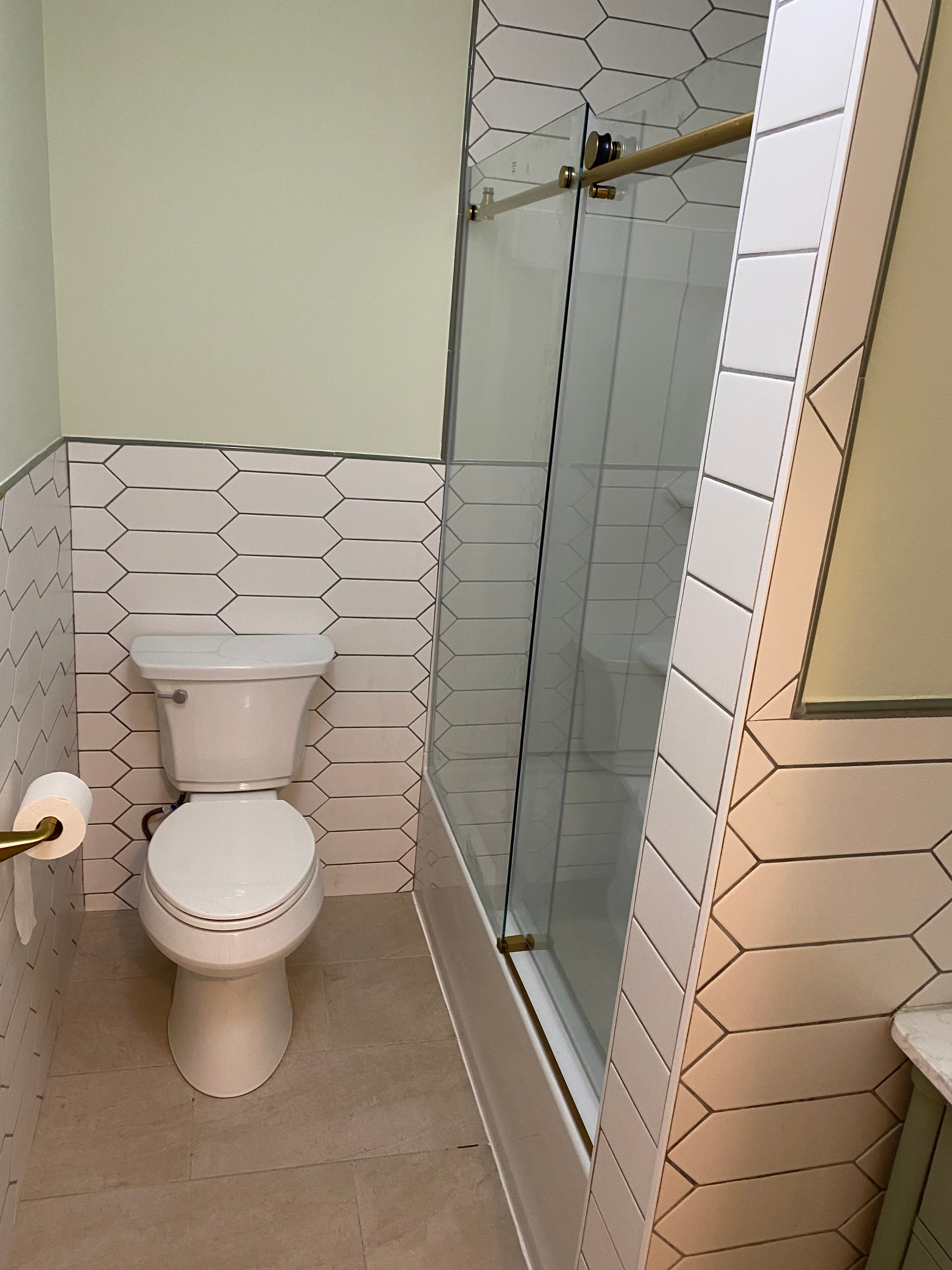 finished bathroom with new toilet and tiled walls and floor and painted walls